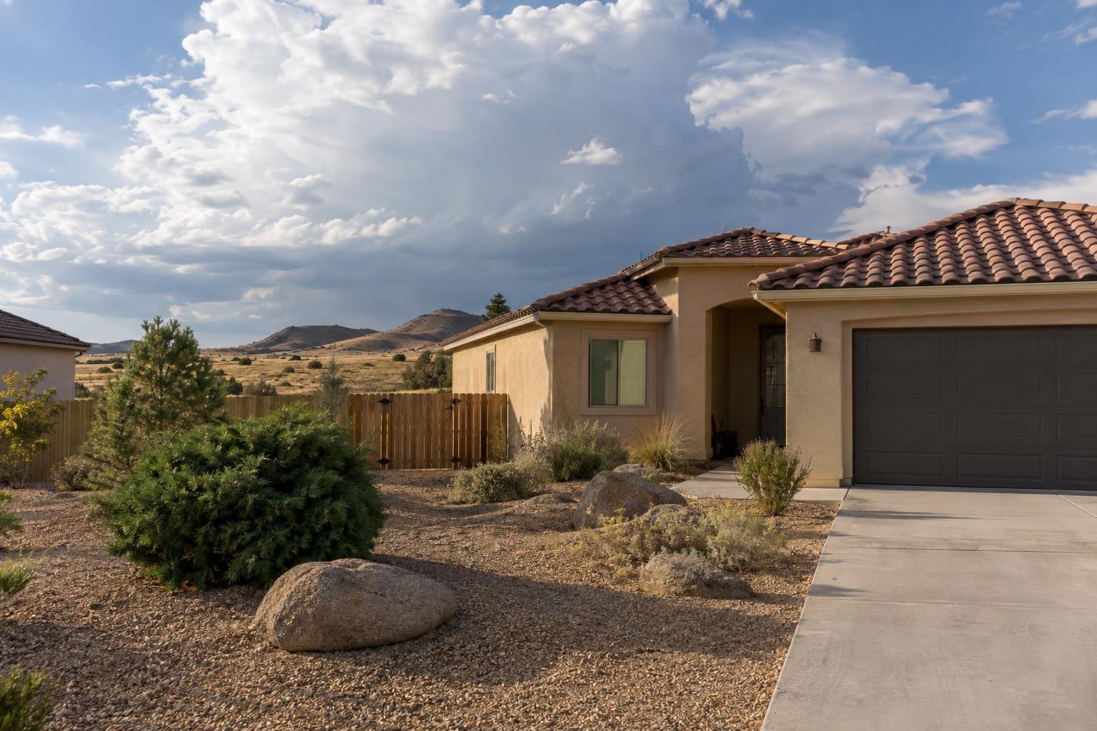 A newer stucco home in Prescott Valley with a gravel yard and boulders